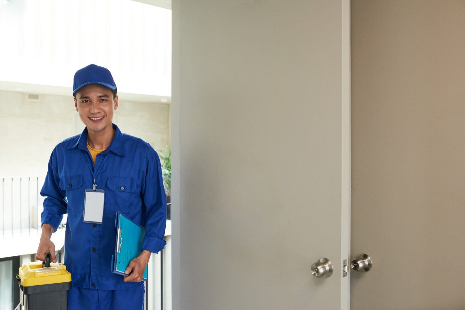 Smiling young handyman with toolbox entering home